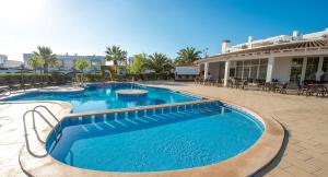 a swimming pool in a resort with tables and chairs at Ona Village Cala d'Or in Cala d´Or