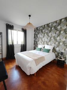 a bedroom with a large white bed with a floral wallpaper at Les jardins Ducarouge 1 climatisé in Digoin