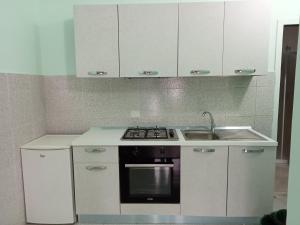 a kitchen with white cabinets and a stove and a sink at Frajà Resort in Palmi
