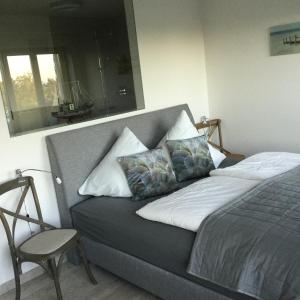 un lit avec deux oreillers et une chaise dans une chambre dans l'établissement Apartment Meeresrauschen -mit Meerblick oberstes OG, à Binz