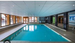 a large swimming pool with blue water in a building at Montagne Les Orres in Les Orres