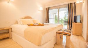 a bedroom with a large white bed with a television at Ona Village Cala d'Or in Cala d´Or