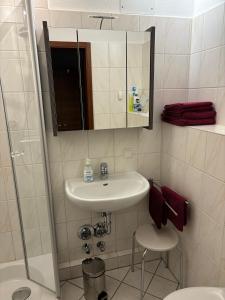 ein Badezimmer mit einem Waschbecken, einem Spiegel und einem Stuhl in der Unterkunft Apartment Pahl in Wolfshagen