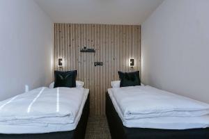 twee bedden in een hotelkamer met witte lakens en zwarte kussens bij House 55 in Sölden