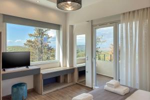 a bedroom with a tv and a large window at AéNaos Luxury Villa with Pool in Galatas in Galatás