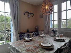 een eetkamer met een houten tafel met borden en wijnglazen bij Maison Le Petit Bonheur in Soturac