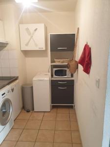 a small kitchen with a washer and a microwave at L' Appartement du Quai Neuf Parking privé - Gare à 5min in Béziers