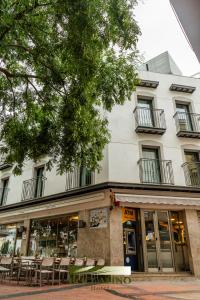 a building with tables and chairs in front of it at Hotel Boccalino Sitges in Sitges