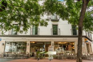 a building with tables and chairs in front of it at Hotel Boccalino Sitges in Sitges