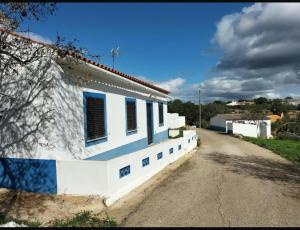 a white house with blue windows and a dirt road at Country House Silves in Silves