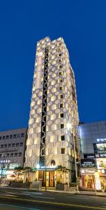 a tall building is lit up at night at Hotel The Designers Cheongnyangni in Seoul