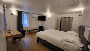 エヴルーにあるHotel de Normandieのベッドと机とテレビのある寝室
