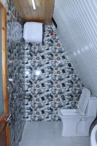 ein Badezimmer mit Toilette und Steinwand in der Unterkunft Eva Cabins in Dalhousie