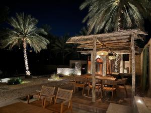 a restaurant with a table and chairs and palm trees at Muskad in Al Ḩamrāʼ