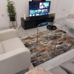 a living room with a tv and a glass table at Wigan - Apartment - Sleeps 3 - Parking - Stadium in Wigan