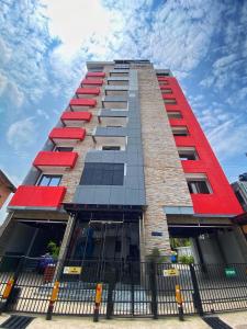 a tall building with red windows and a fence at Mansah Plus Hotel and Apartments in Accra
