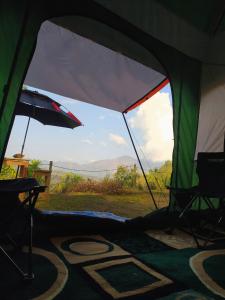 a tent with a chair and an umbrella at Kintamani Adventures 'Finding Peace In The Wilderness' in Kintamani