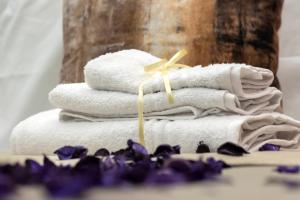 a stack of towels and purple flowers on a table at Dea Suite in Bagheria