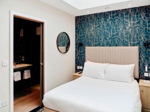 a bedroom with a white bed and a blue wall at Hotel De Normandie in Saint Helier Jersey