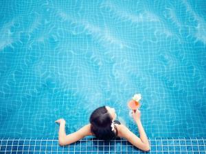 a woman laying in a pool holding a ball and flowers at Ibis Saigon Airport in Ho Chi Minh City