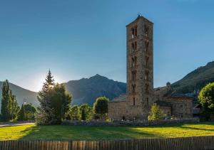 un antiguo edificio de piedra con una torre en un campo en Apartament Dúplex amb encant a l'alta muntanya - Saraís, en Durro