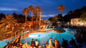 a group of people sitting around a pool at night at Camping 4 étoiles - Parc aquatique - efacfc in Hyères