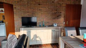 a living room with a tv on a brick wall at Ferienhaus mit Meerblick in Lemmer