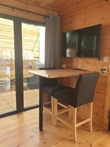 einen Tisch und einen Stuhl in einem Zimmer mit einem TV in der Unterkunft Studio cabane in La Bucaille