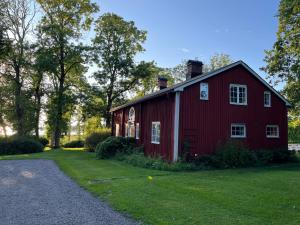 a red barn with a gravel driveway in front of it at Romantic Villa in historic setting with lake view in Säffle