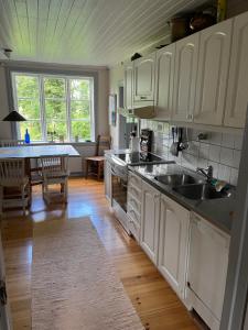a kitchen with white cabinets and a sink and a table at Romantic Villa in historic setting with lake view in Säffle