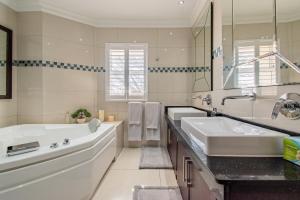 a white bathroom with two sinks and a tub at Serene Simbithi Penthouse Oasis in Shakaʼs Rock +34 photos