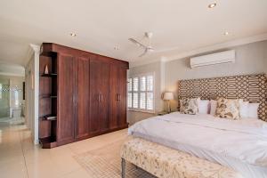 a large bedroom with a large bed and a wooden cabinet at Serene Simbithi Penthouse Oasis in Shakaʼs Rock