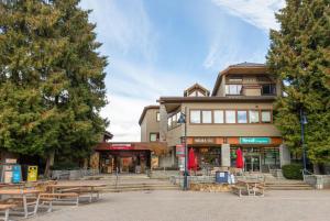 un edificio con mesas de picnic delante de él en Tantalus Penthouse Mountain and Village Views, en Whistler