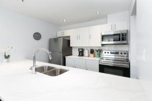 Una cocina blanca con fregadero y refrigerador. en Tantalus Penthouse Mountain and Village Views, en Whistler 13 fotos más