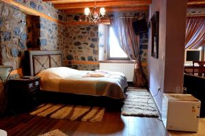 a bedroom with a bed and a window and a television at To Spitiko in Palaios Agios Athanasios