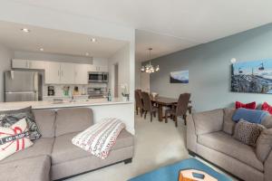 Una sala de estar con un sofá y una cocina. en Tantalus Penthouse Mountain and Village Views, en Whistler