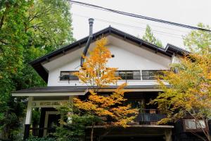 una casa bianca con alberi di fronte di 雪花菜山荘 a Hakuba
