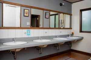 un bagno pubblico con tre lavandini e specchi di 雪花菜山荘 a Hakuba