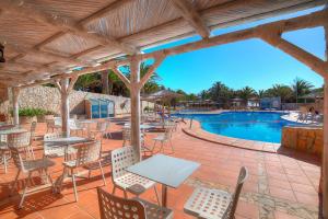 a patio with tables and chairs next to a swimming pool at SBH Monica Beach Resort in Costa Calma