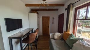a living room with a couch and a desk with a tv at Jera Pince és Vendégház in Somlóvásárhely