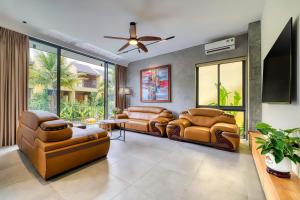 a living room with leather furniture and a ceiling fan at Ancasa villa Hội An in An Bang
