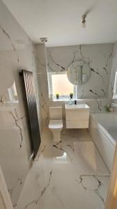 a bathroom with a sink and a toilet and a tub at Silverburn new house with free parking and nice garden in Glasgow +13 photos