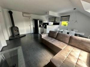 a living room with a brown couch and a kitchen at Apartment and rooms Špes in Mislinja
