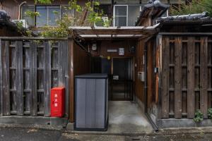 an entrance to a wooden fence with a trash can at Shiki Homes HIKARI in Kyoto