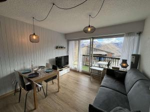 a living room with a couch and a table at Studio cabine rénové, 4 couchages, pied des pistes, parking, balcon sud - FR-1-297-160 in Auris