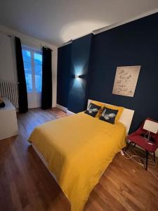 a bedroom with a yellow bed and a red chair at Appartement entre lacs et montagnes in Saint-Claude