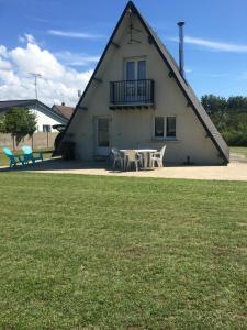 a house with a table and chairs in front of it at Gîte Les trois pins in Saint-Germain-sur-Ay