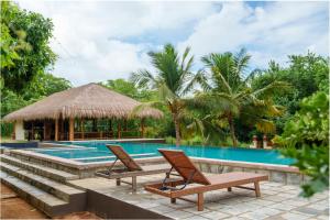 una piscina del resort con due sedie e un gazebo di Omkara Rekawa a Tangalle