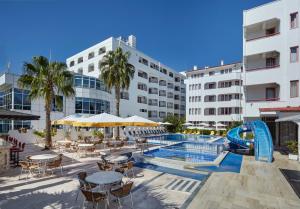 a hotel with a pool and tables and chairs at Hotel Billurcu in Ayvalık
