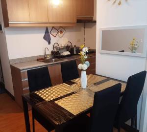 a dining room table with a vase of flowers on it at Arezzo Place Davao - Condo Rentals WITH FREE POOL, 200MBPS CONNECTION in Lanang
